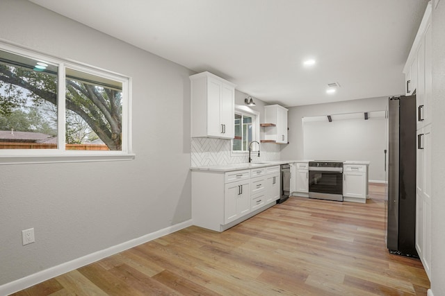 kitchen featuring sink, white cabinetry, stainless steel appliances, decorative backsplash, and light wood-type flooring