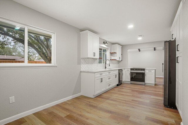 kitchen with light countertops, backsplash, appliances with stainless steel finishes, light wood-type flooring, and baseboards