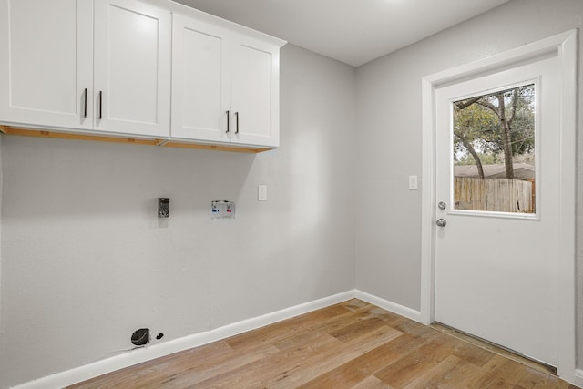 washroom featuring light wood-type flooring, cabinet space, hookup for a washing machine, and baseboards