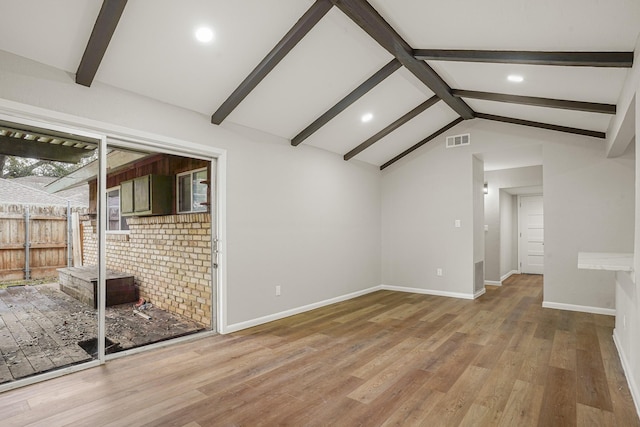 spare room featuring lofted ceiling with beams, wood finished floors, visible vents, and baseboards