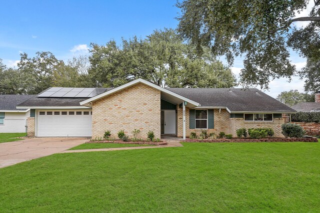 ranch-style house featuring a garage, a front lawn, and solar panels