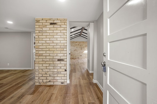 corridor with brick wall, baseboards, wood finished floors, and recessed lighting