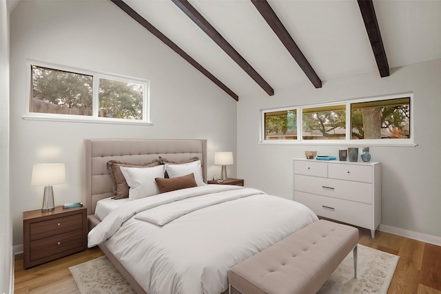 bedroom with light wood-style floors, lofted ceiling with beams, and baseboards