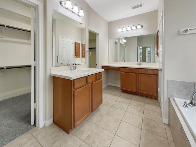 bathroom featuring tile patterned flooring, tiled tub, and vanity