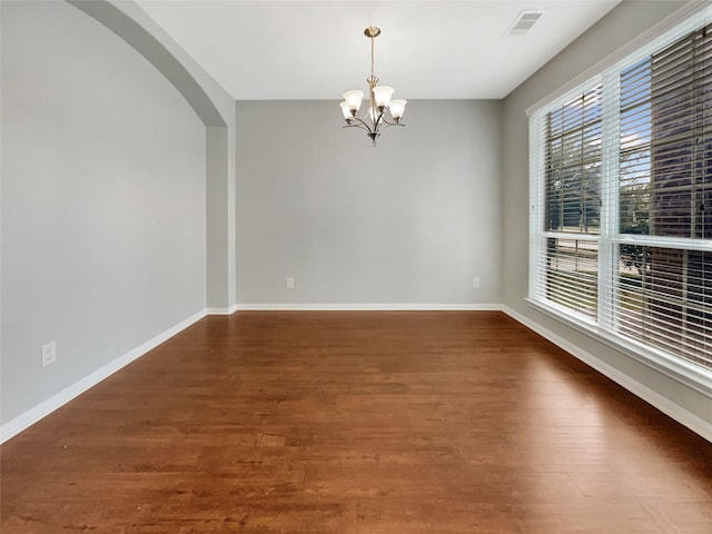 unfurnished room featuring dark hardwood / wood-style flooring, plenty of natural light, and a chandelier