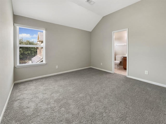 interior space featuring lofted ceiling, carpet floors, and ensuite bath