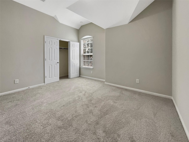 unfurnished bedroom with lofted ceiling, light carpet, and a closet