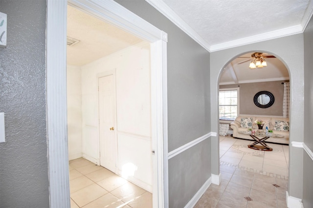 hallway featuring crown molding, light tile patterned flooring, and a textured ceiling