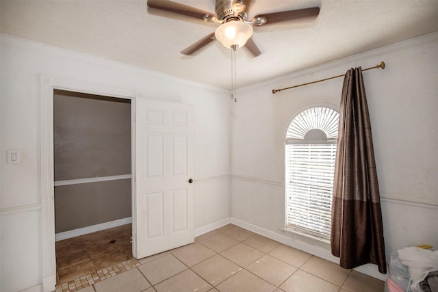 empty room with crown molding, ceiling fan, a textured ceiling, and light tile patterned floors