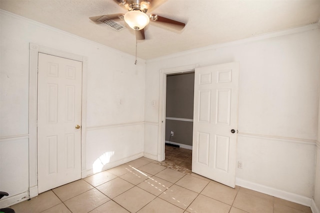 unfurnished bedroom with light tile patterned floors, ornamental molding, and ceiling fan