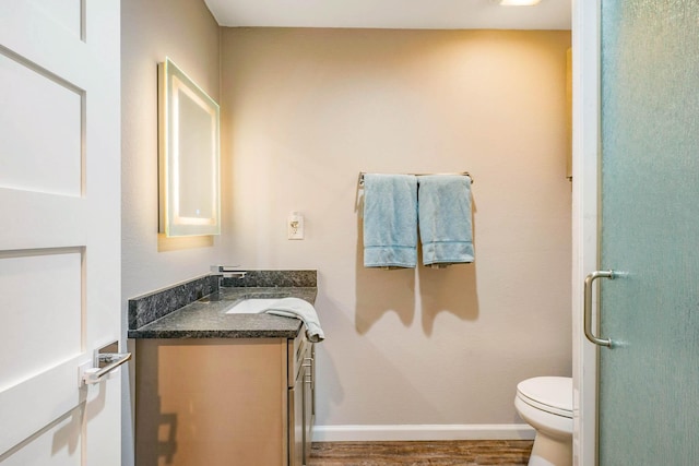 bathroom featuring vanity, wood-type flooring, an enclosed shower, and toilet