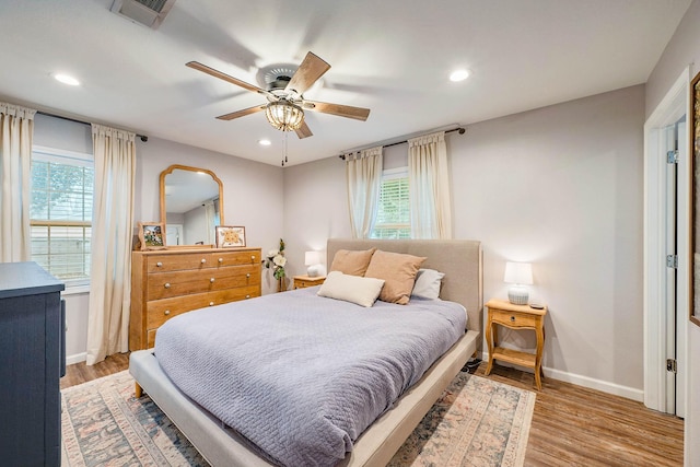 bedroom featuring multiple windows, ceiling fan, and light wood-type flooring