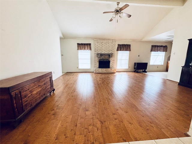 unfurnished living room featuring a brick fireplace, ceiling fan, vaulted ceiling, and wood finished floors