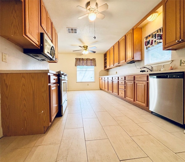 kitchen with light countertops, visible vents, appliances with stainless steel finishes, brown cabinetry, and a ceiling fan