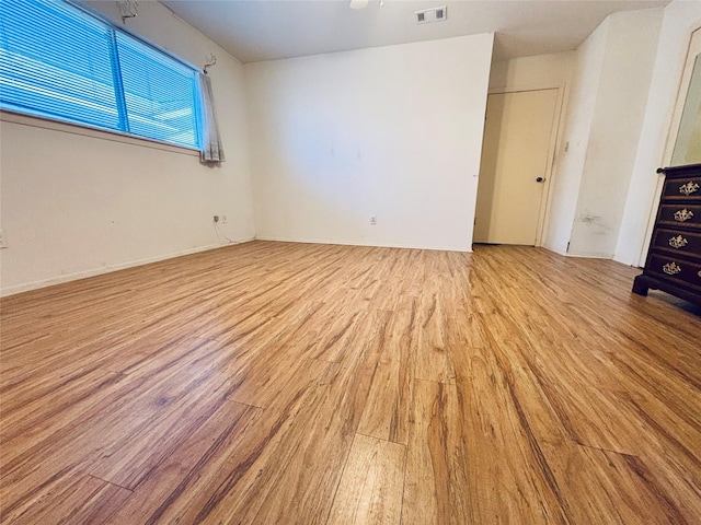 empty room with light wood finished floors and visible vents