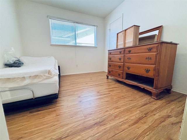 bedroom featuring light wood finished floors and baseboards