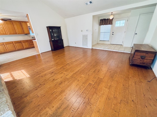 unfurnished living room featuring high vaulted ceiling, light wood-style floors, visible vents, and a ceiling fan