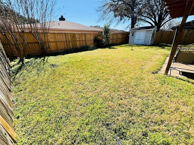 view of yard featuring a storage shed, an outbuilding, and a fenced backyard