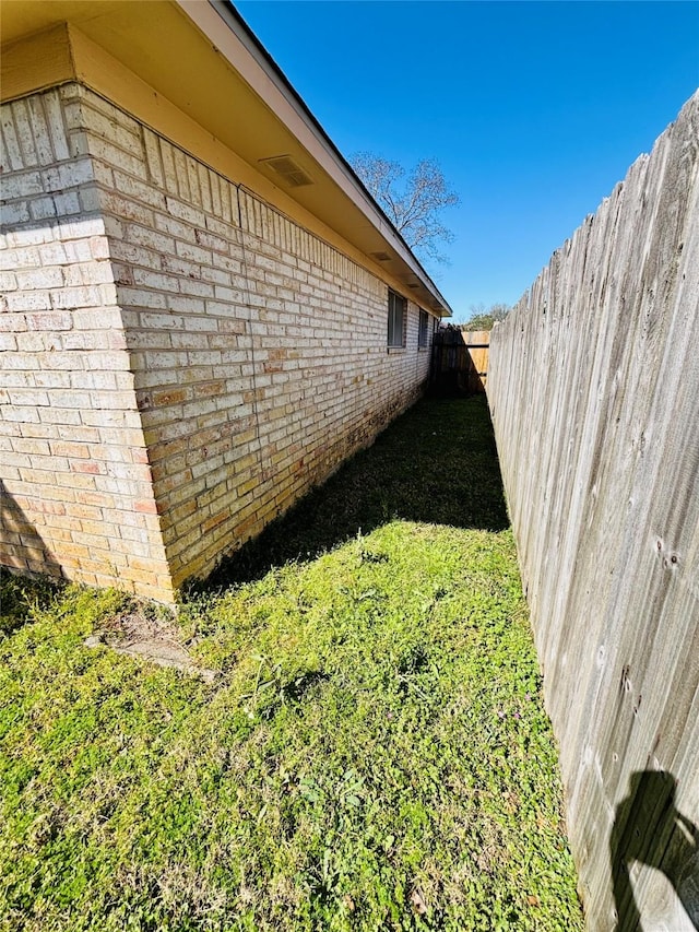 view of side of property featuring brick siding and fence