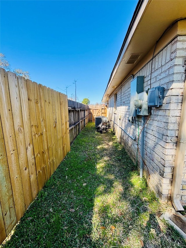 view of yard featuring central AC unit and fence