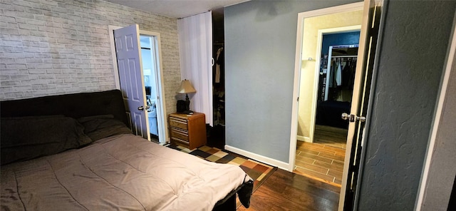 bedroom featuring brick wall and dark hardwood / wood-style floors