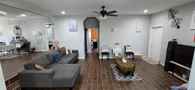 living room featuring ceiling fan, dark hardwood / wood-style flooring, and a textured ceiling