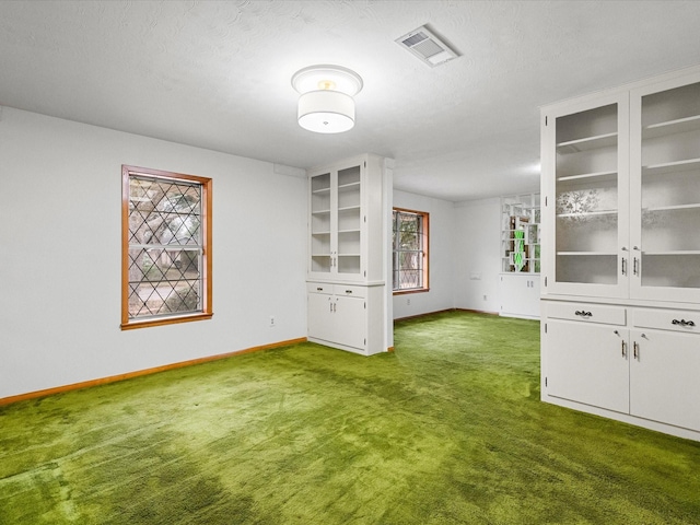 interior space featuring baseboards, visible vents, dark carpet, and a textured ceiling