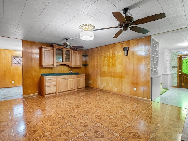 kitchen with dark countertops, wood walls, baseboards, and glass insert cabinets