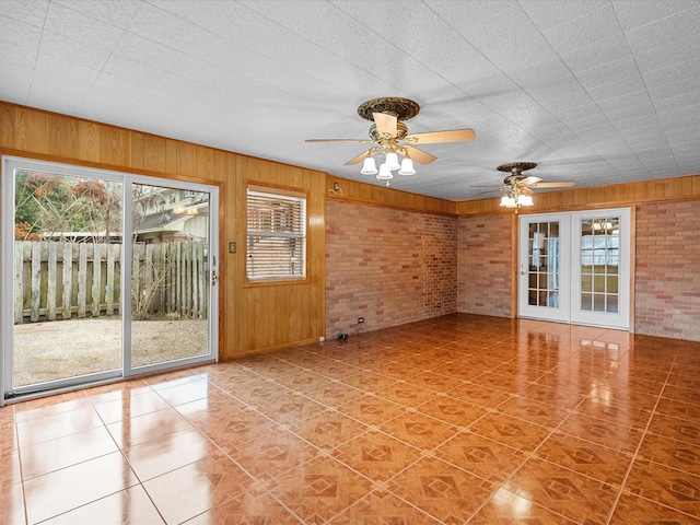 tiled empty room with brick wall, a wealth of natural light, and wooden walls