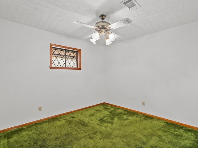 carpeted spare room featuring baseboards, visible vents, and ceiling fan