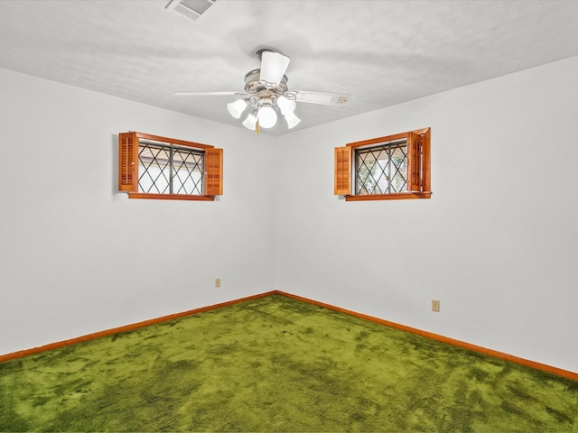 empty room featuring ceiling fan, carpet floors, visible vents, and baseboards