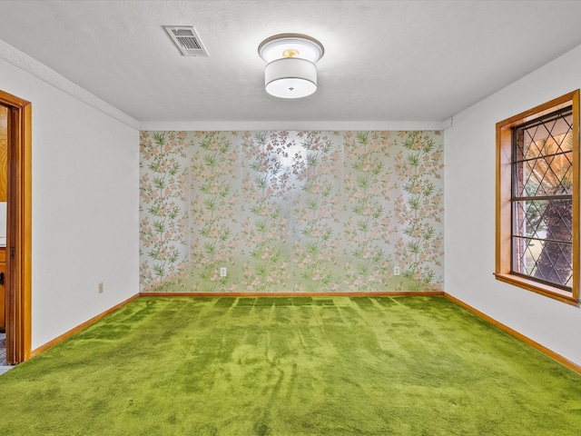 spare room featuring carpet floors, wallpapered walls, baseboards, and visible vents