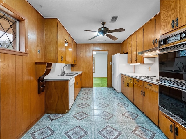 kitchen featuring light countertops, visible vents, brown cabinetry, white appliances, and under cabinet range hood