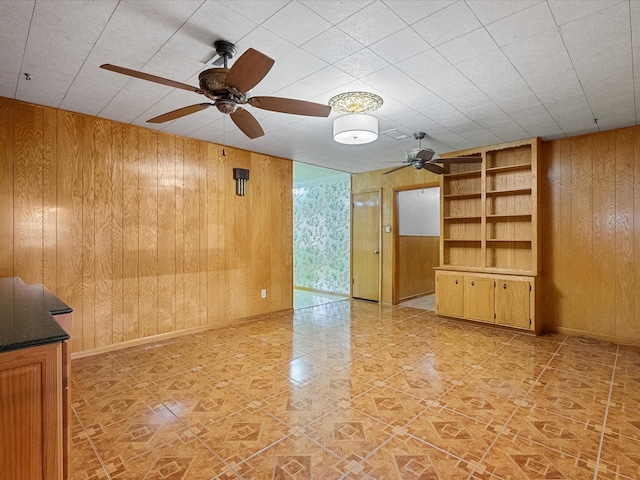 spare room featuring baseboards, a ceiling fan, and wooden walls