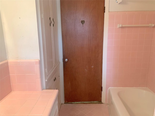 bathroom featuring a bathing tub, tile patterned flooring, and tile walls