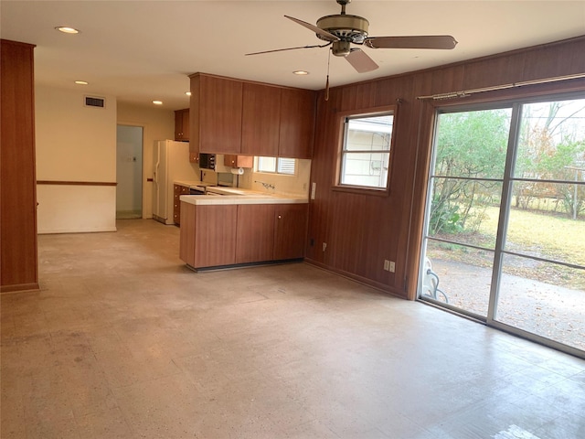 kitchen featuring ceiling fan, plenty of natural light, wooden walls, and kitchen peninsula