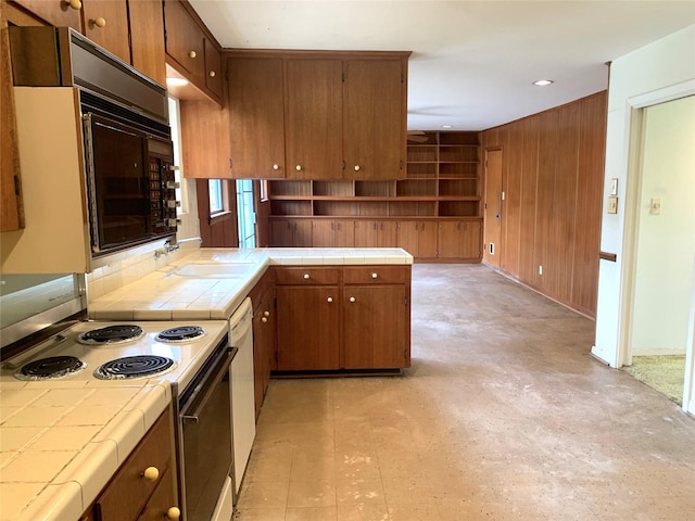 kitchen with sink, electric range, white dishwasher, tile counters, and kitchen peninsula