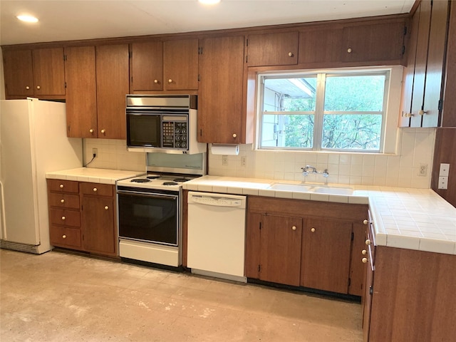 kitchen with sink, white appliances, tile countertops, and decorative backsplash