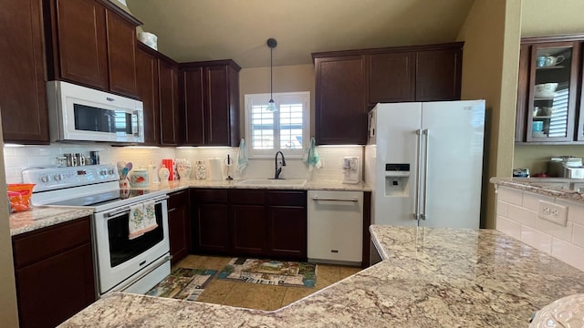 kitchen with tasteful backsplash, sink, hanging light fixtures, light stone counters, and white appliances