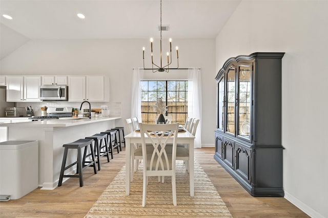 dining area with a notable chandelier, baseboards, light wood-style floors, and visible vents