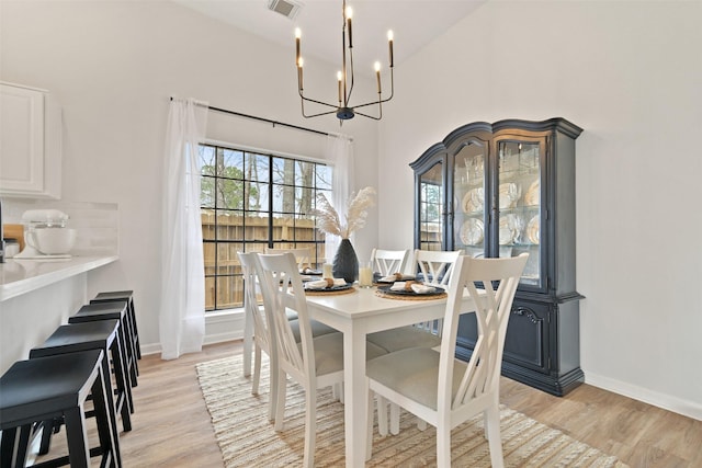 dining room with light wood-style flooring, a notable chandelier, baseboards, and visible vents