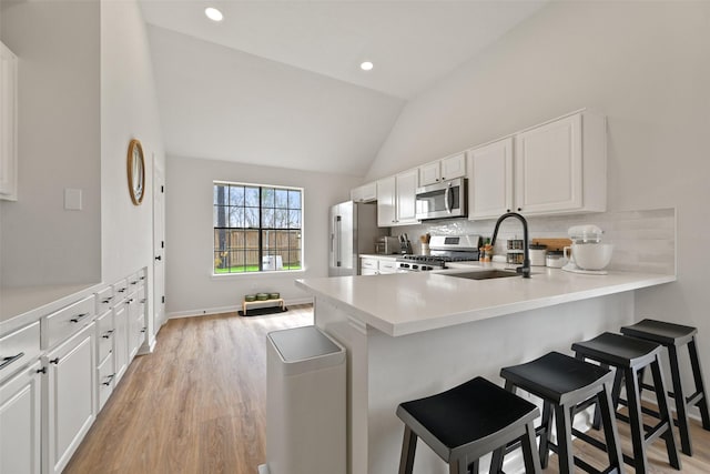 kitchen featuring a sink, stainless steel appliances, backsplash, and a breakfast bar