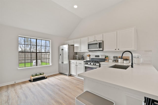 kitchen with backsplash, light countertops, white cabinets, stainless steel appliances, and a sink