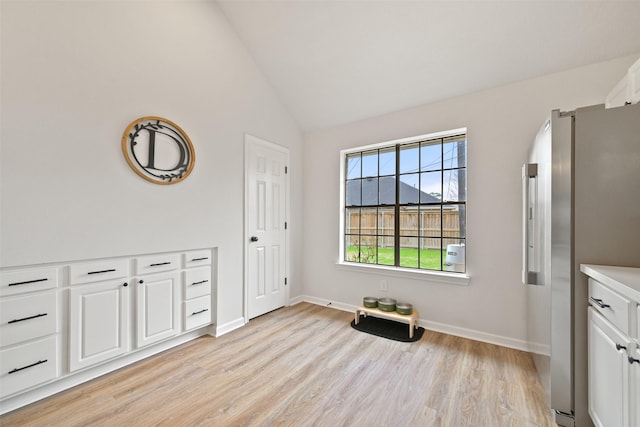 interior space featuring baseboards, lofted ceiling, and light wood-style floors