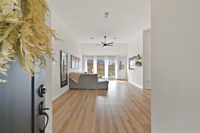 entrance foyer with ceiling fan, baseboards, light wood-style flooring, and a towering ceiling