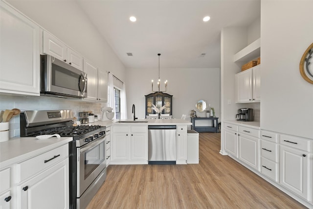 kitchen featuring a peninsula, decorative backsplash, light countertops, appliances with stainless steel finishes, and light wood-type flooring