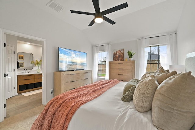 bedroom with visible vents, lofted ceiling, ensuite bath, a ceiling fan, and a sink