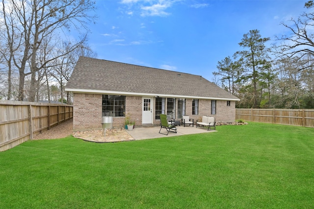 rear view of house featuring brick siding, roof with shingles, a fenced backyard, a yard, and a patio area