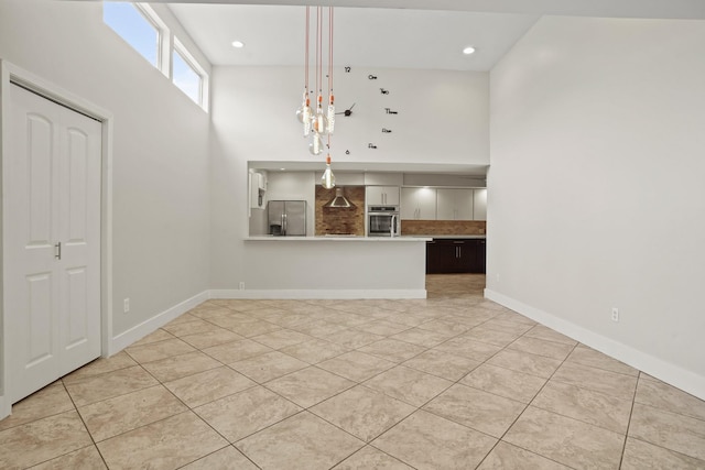 unfurnished dining area featuring light tile patterned floors and a high ceiling