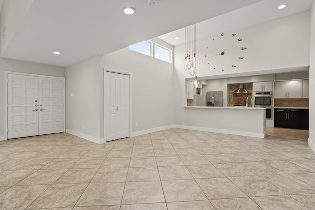 unfurnished living room featuring sink, a high ceiling, and light tile patterned floors